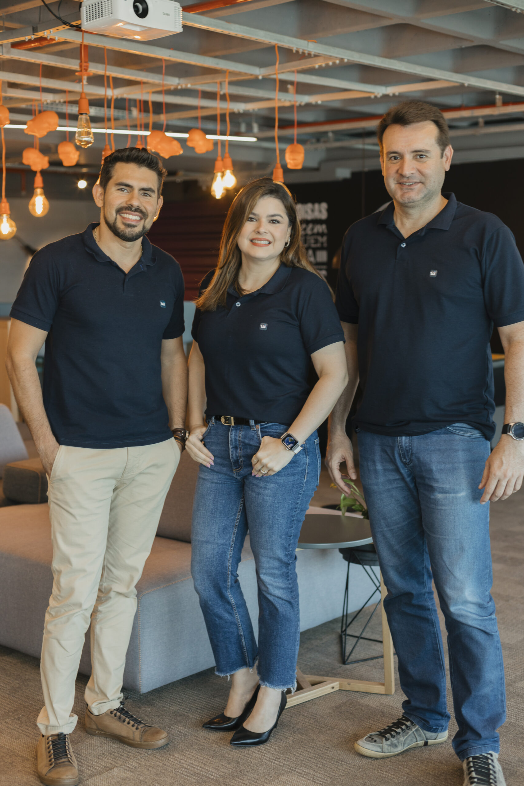 Três integrantes da equipe Wing sorrindo no escritório
